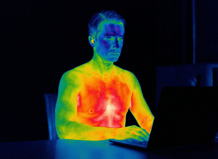 Person sitting calmly at a desk viewed through thermal imaging, revealing intense emotional heat beneath a composed exterior — representing the hidden dominant emotion every prospect carries
