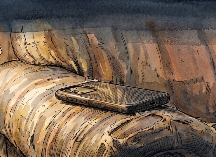 A mobile phone lying face down on a couch cushion in low lamplight.